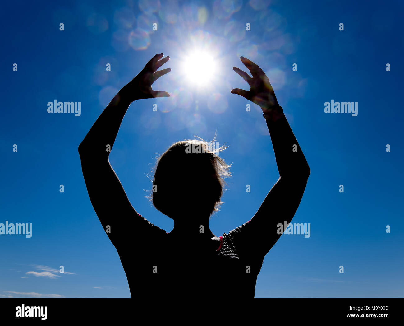 Silhouette of a girl against the background of the sun and blue sky ...