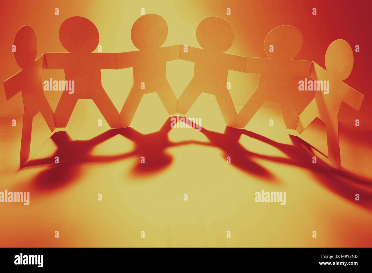 Team of paper chain people in a row holding hands Stock Photo - Alamy