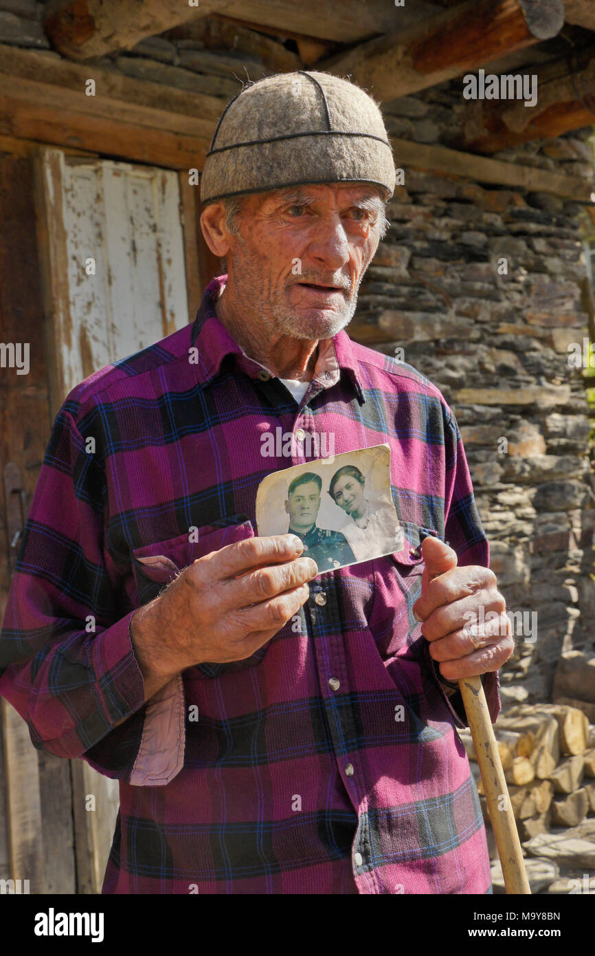 An elderly man proudly displays a photograph, taken in 1958, of himself and his wife, Ushguli, Upper Svaneti, Georgia Stock Photo