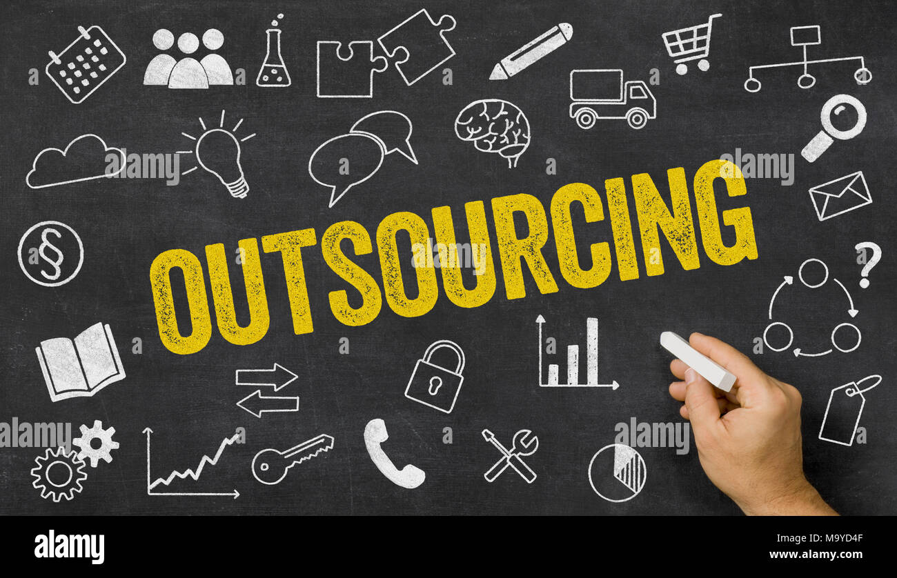 Outsourcing written on a blackboard with icons Stock Photo