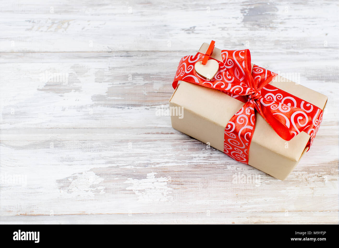 Gift box with red ribbon on white old wooden table. The concept of love ...