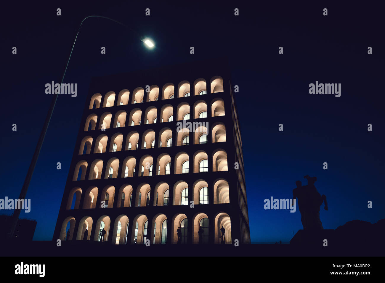 Rome (Italy) - Palazzo della Civiltà Italiana by Night, Street Lamp and Dioscuri equestrial statue silhouette Stock Photo