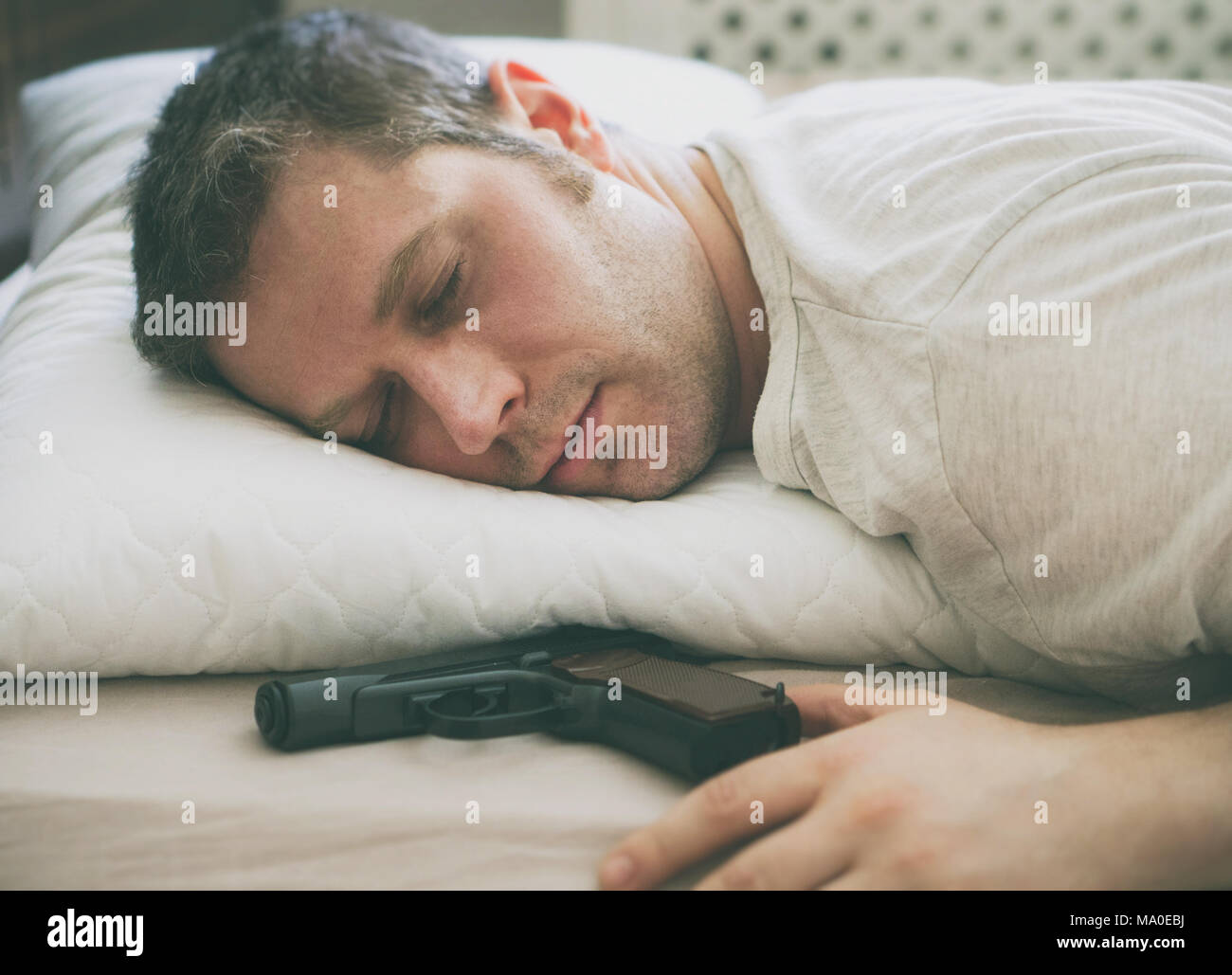 Man sleeping in bed with gun near his hand Stock Photo Alamy