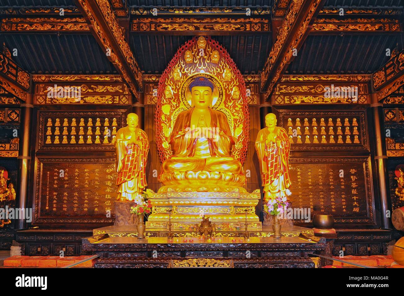 The golden statue of the Buddha and two monks of the Da Ci'en Temple, Xian, China. Stock Photo