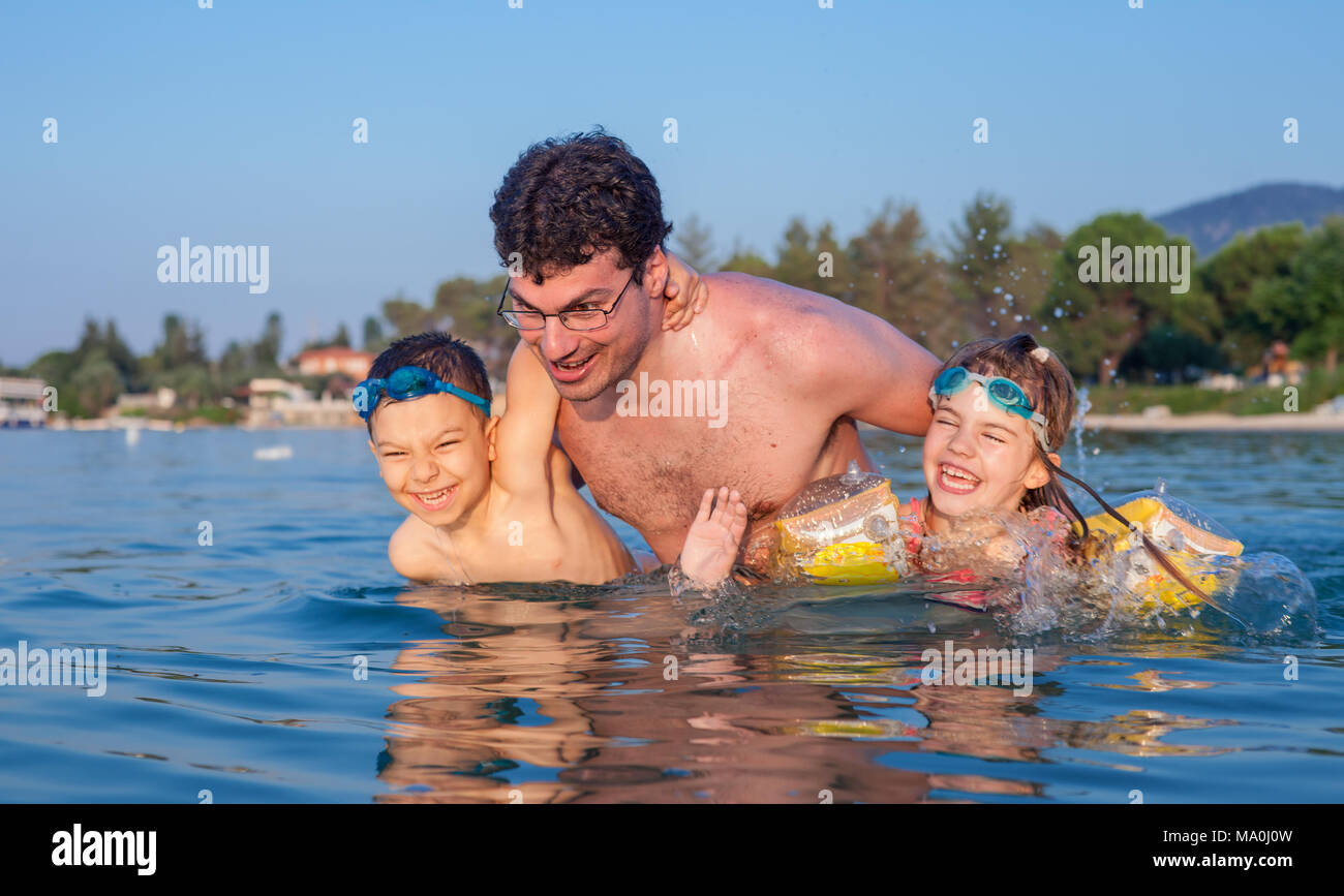 Young father having fun in sea waters during vacation in a hot summer day with his son and daughter. Stock Photo