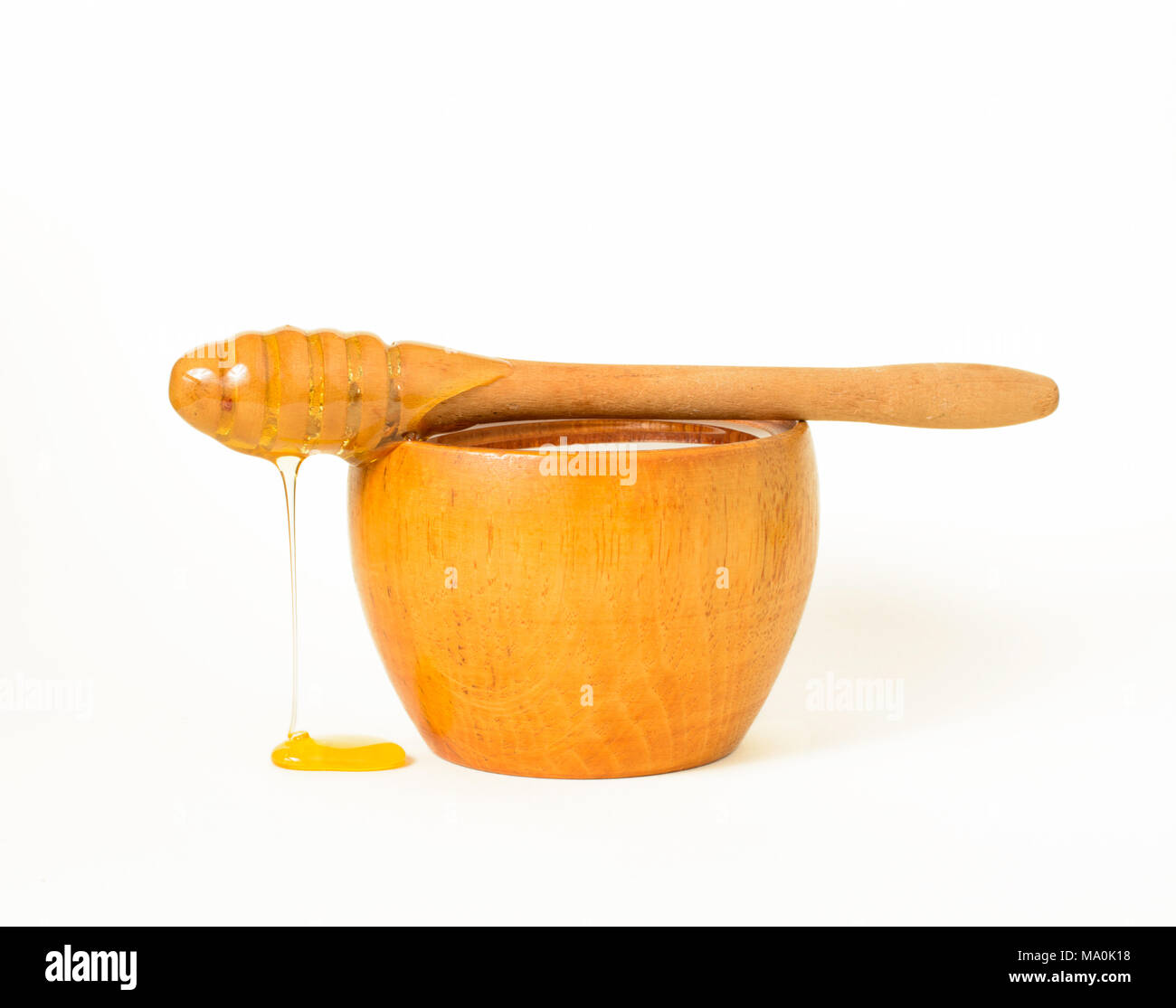 Honey in a wooden bowl and a honey dipper, a special kind of kitchen utensil used to collect honey from a vessel. Stock Photo