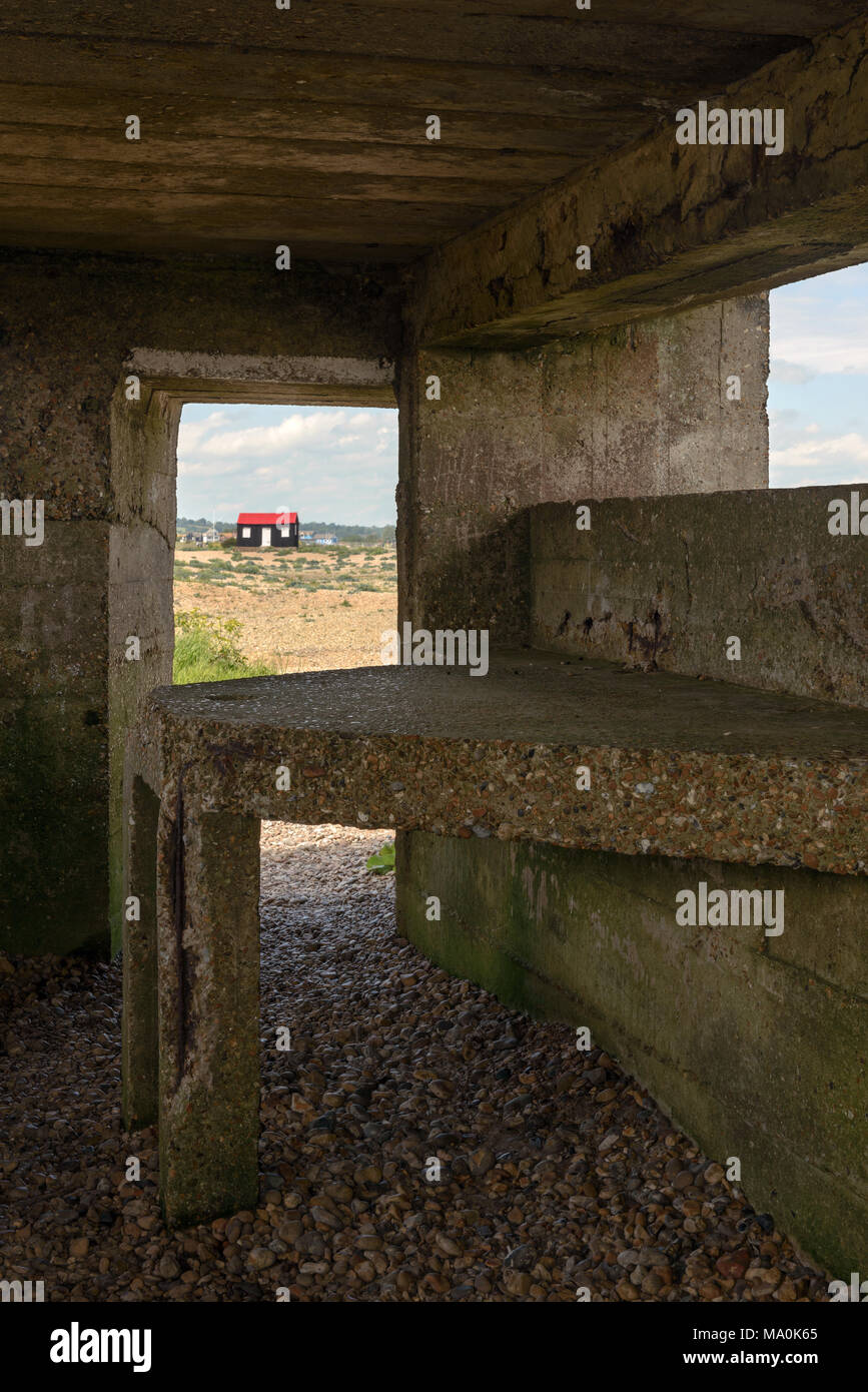 Looking from within an old WW2 pill box at Rye harbour in West Sussex towards the little hut with the red roof. Stock Photo