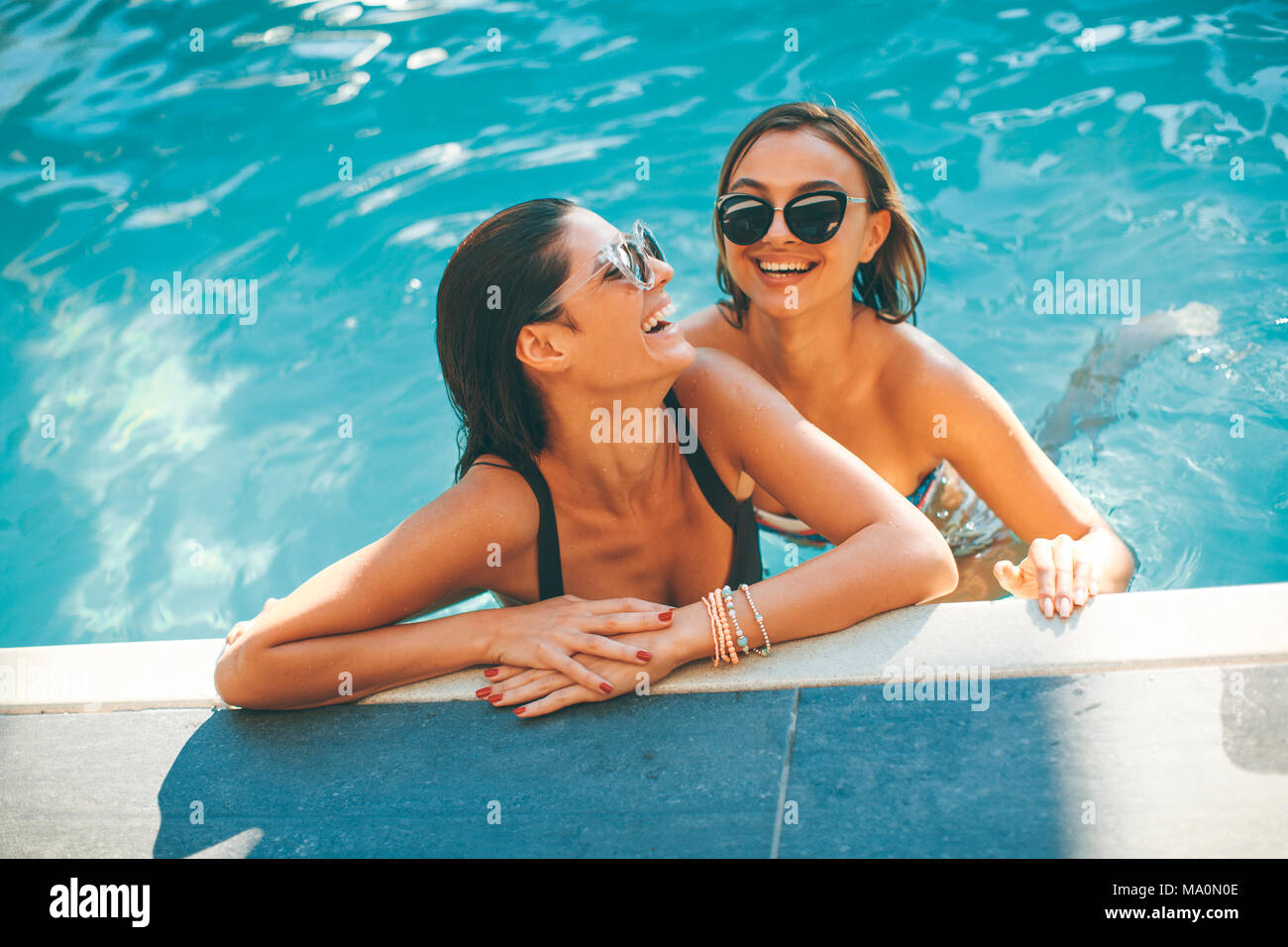 Young women having fun by the pool at hot summer day Stock Photo