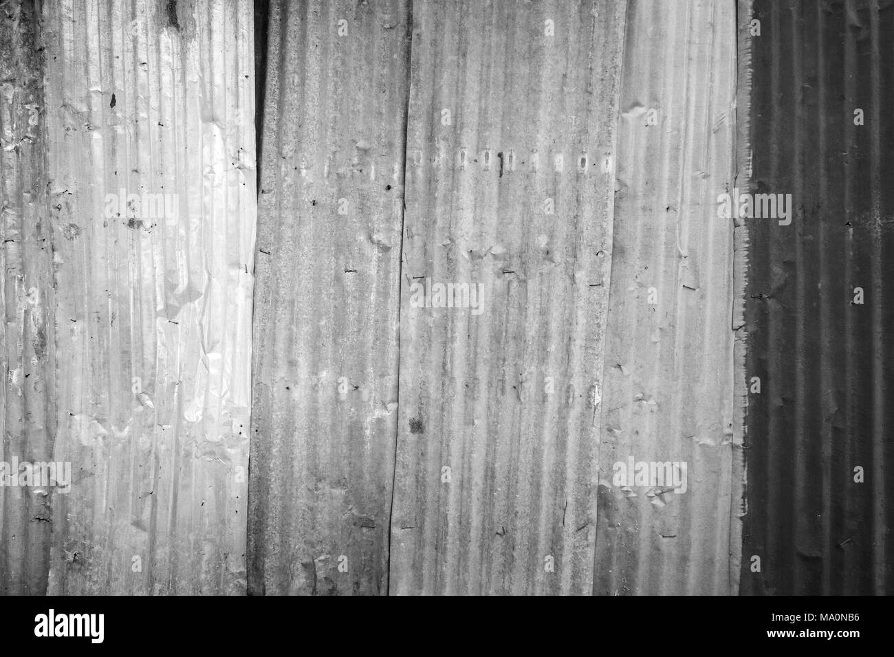 Rusty and corrugated iron metal construction site wall texture background with vignette in black and white. Stock Photo