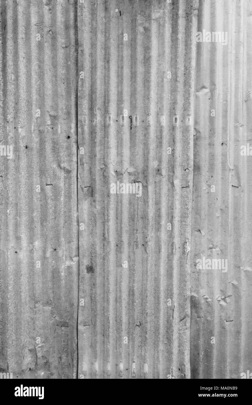 Faded and corrugated iron metal construction site wall texture background in black and white. Stock Photo