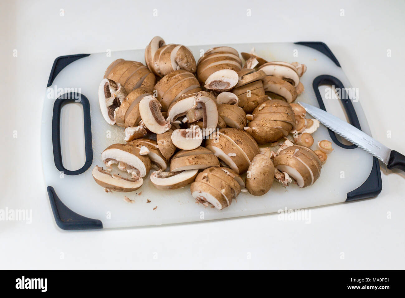 A pile of sliced chestnut mushrooms (Agaricus bisporus) on a white chopping board Stock Photo
