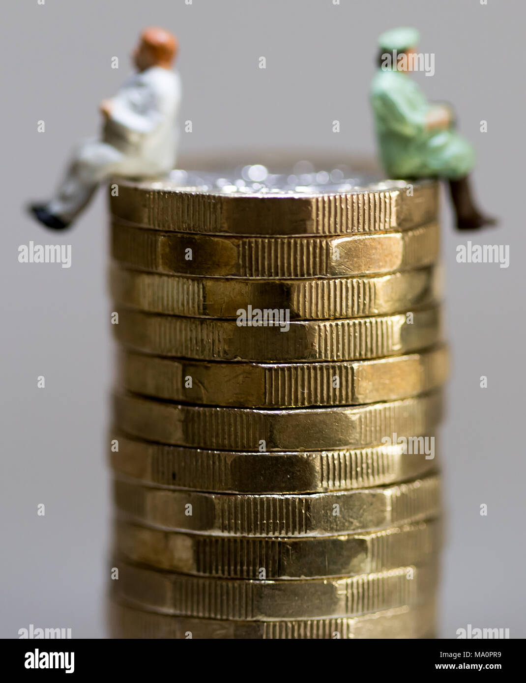 Gender pay equality concept image of man and woman on a stack of pound coins Stock Photo