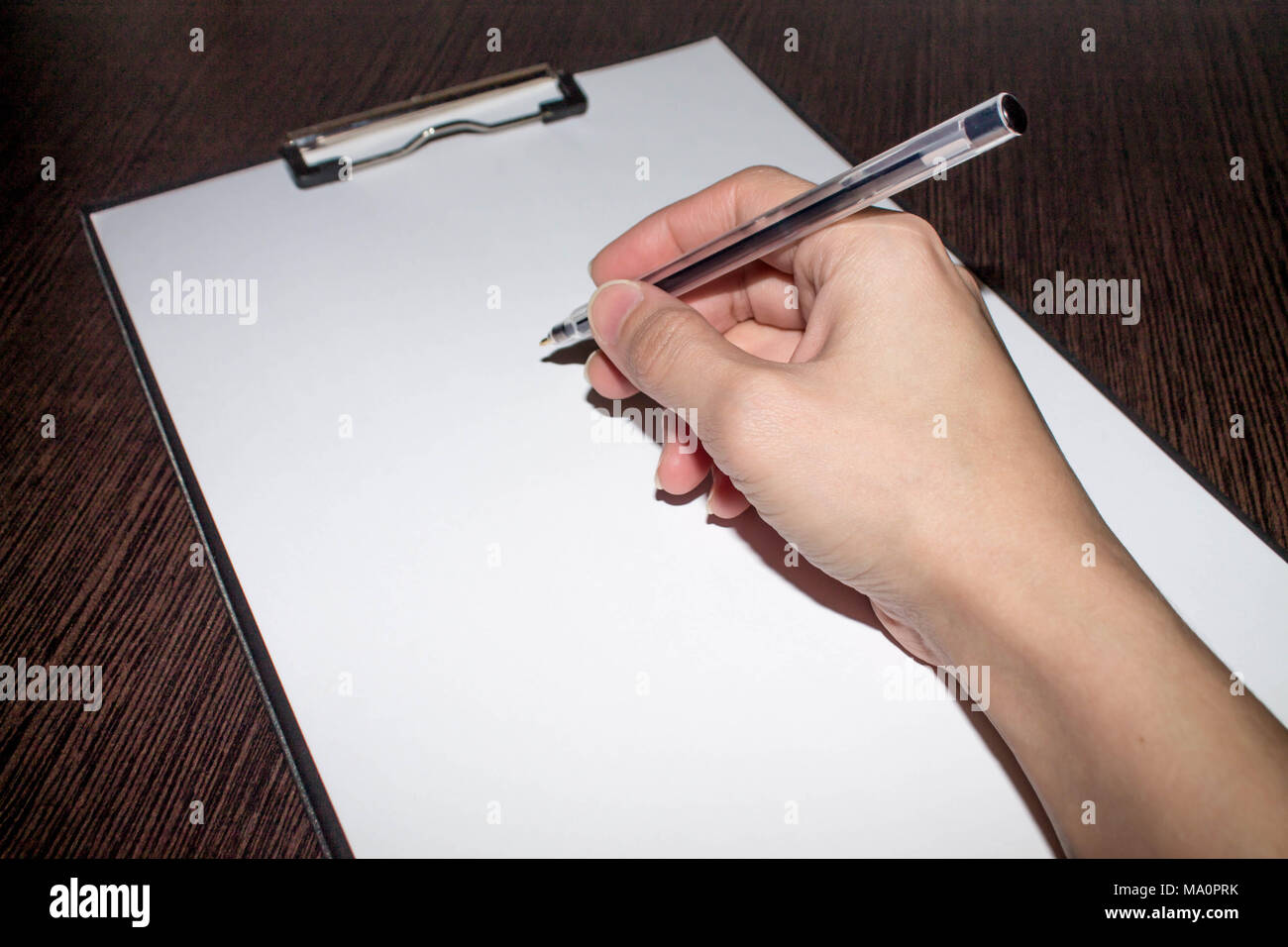 hand and pen above the sheet of paper Stock Photo