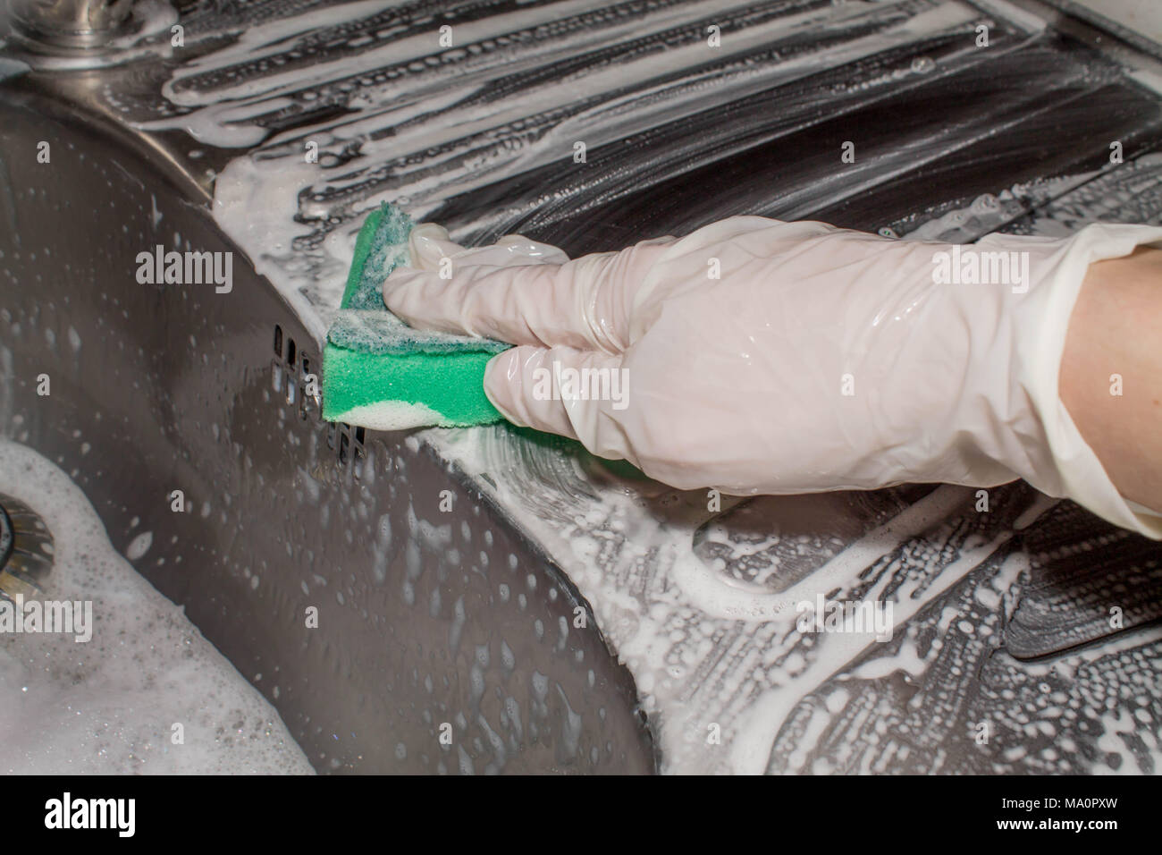 hand in latex glove duster washing the metal sink. cleaning Stock Photo