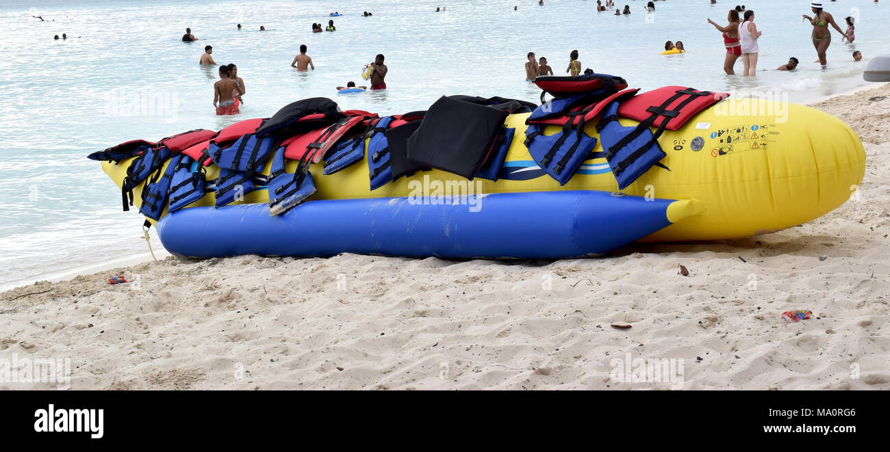 Yellow inflatable banana boat with paddles on busy beach with people