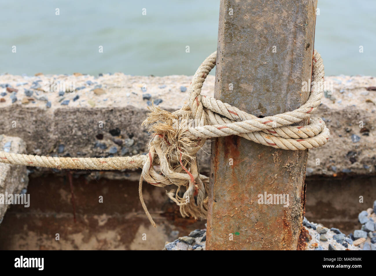 Old fishing boat rope with a Tied Knot around the old concrete