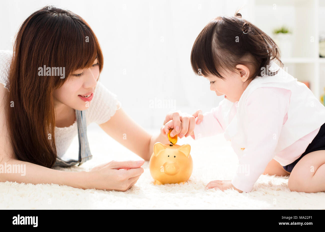 Mother and daughter putting coins into piggy bank Stock Photo - Alamy