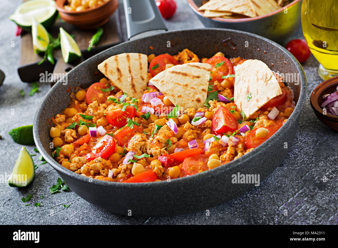 Chili con carne of turkey with chickpeas served with nachos. Chili with meat, nachos, lime, hot