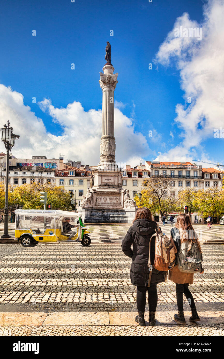 5 March 2018: Lisbon, Portugal - two young women wait to cross the road into Rossio Square. In the centre is the Column of Pedro IV. Stock Photo
