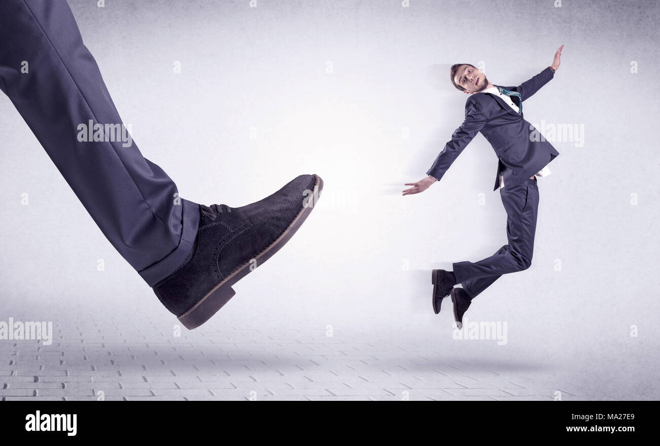 Small young businessman kicked out by a big black shoe Stock Photo Alamy