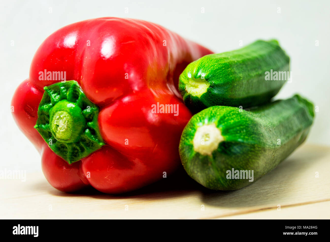 soft focus of fresh red pepper and green zucchini on a white background - capsicum, cocurbita pepo Stock Photo