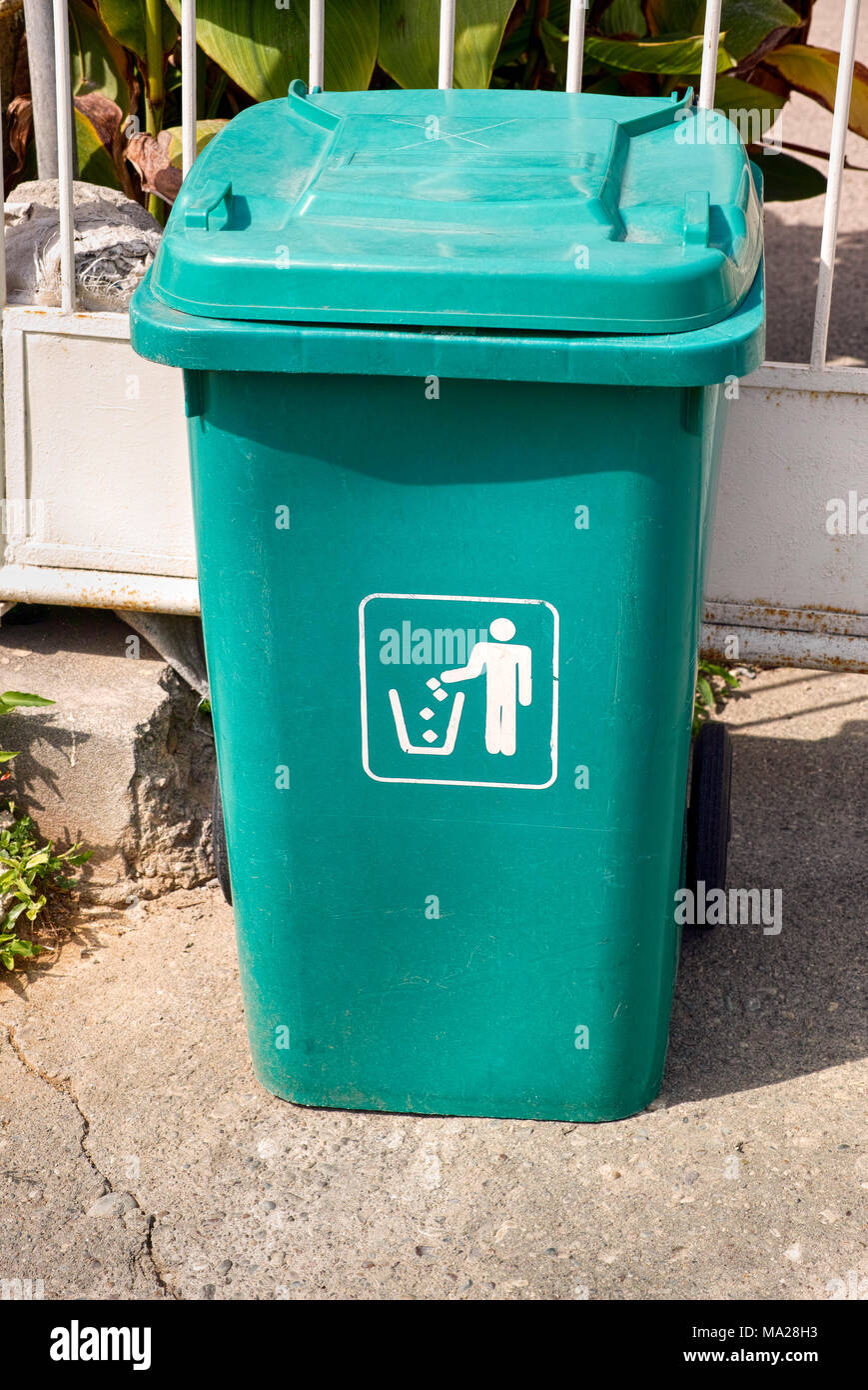 A large, metal, green garbage container and municipal waste, standing on a  dirt road near the fence and trees Stock Photo - Alamy