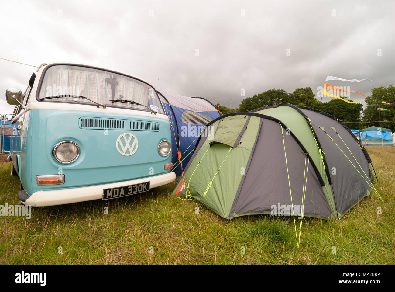 Blue and white vintage VW Camper van parked at a camp site with a tent next to it, Dorset, England, UK Stock Photo