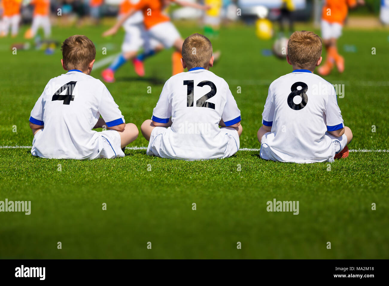 Coaching Youth Soccer. Young Boys Sitting on Football Field and Watching Tournament Game. Football Match for Kids Stock Photo