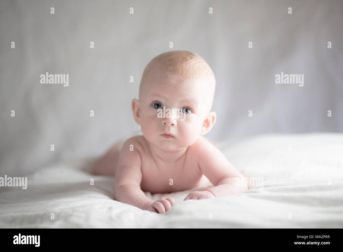 cute baby boy lying on bed with a contemplative look on his face Stock Photo