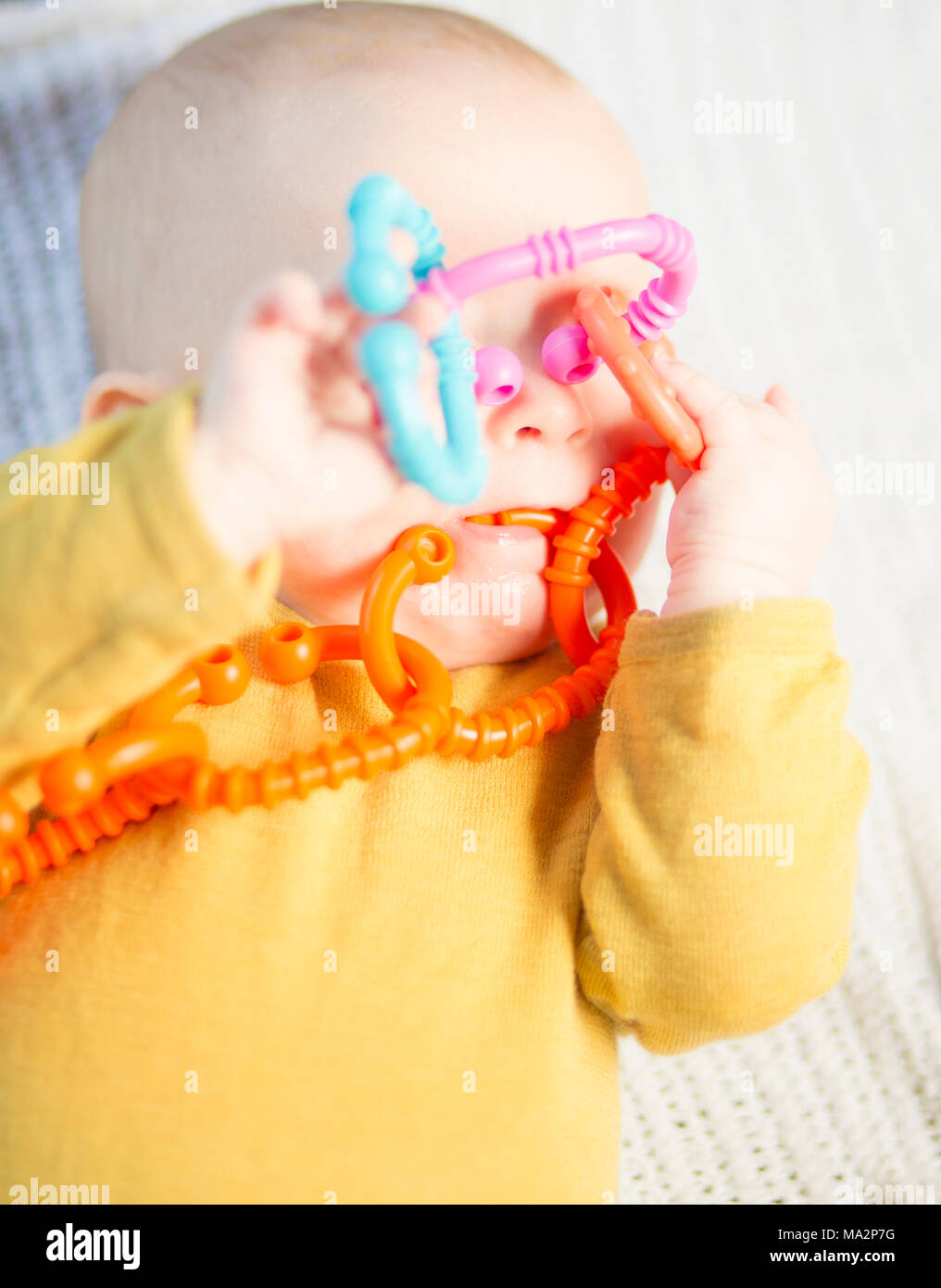 Very cute baby boy playing with ring o' links rattle toy that's