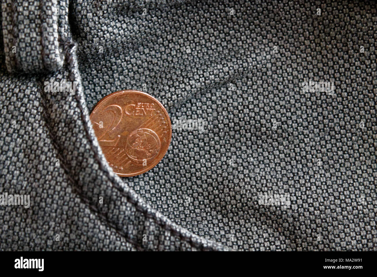 Euro coin with a denomination of 2 euro cent in the pocket of worn brown denim jeans Stock Photo