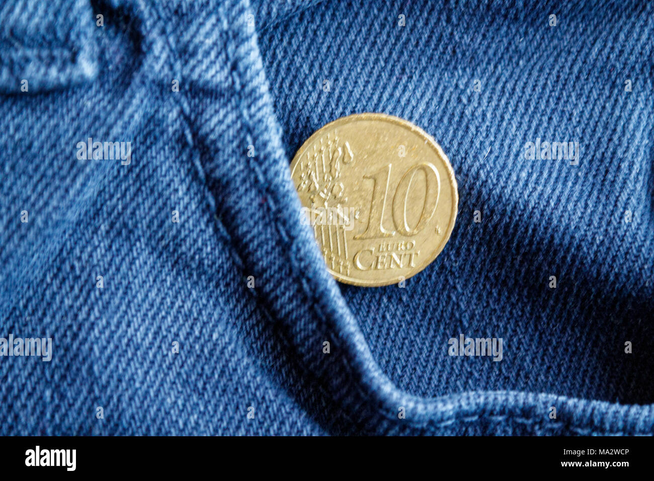 Euro coin with a denomination of ten euro cent in the pocket of worn blue denim jeans Stock Photo