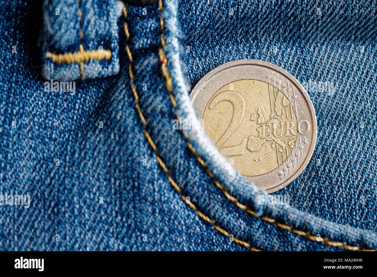 Euro coin with a denomination of 2 euro in the pocket of vintage blue denim jeans Stock Photo Alamy