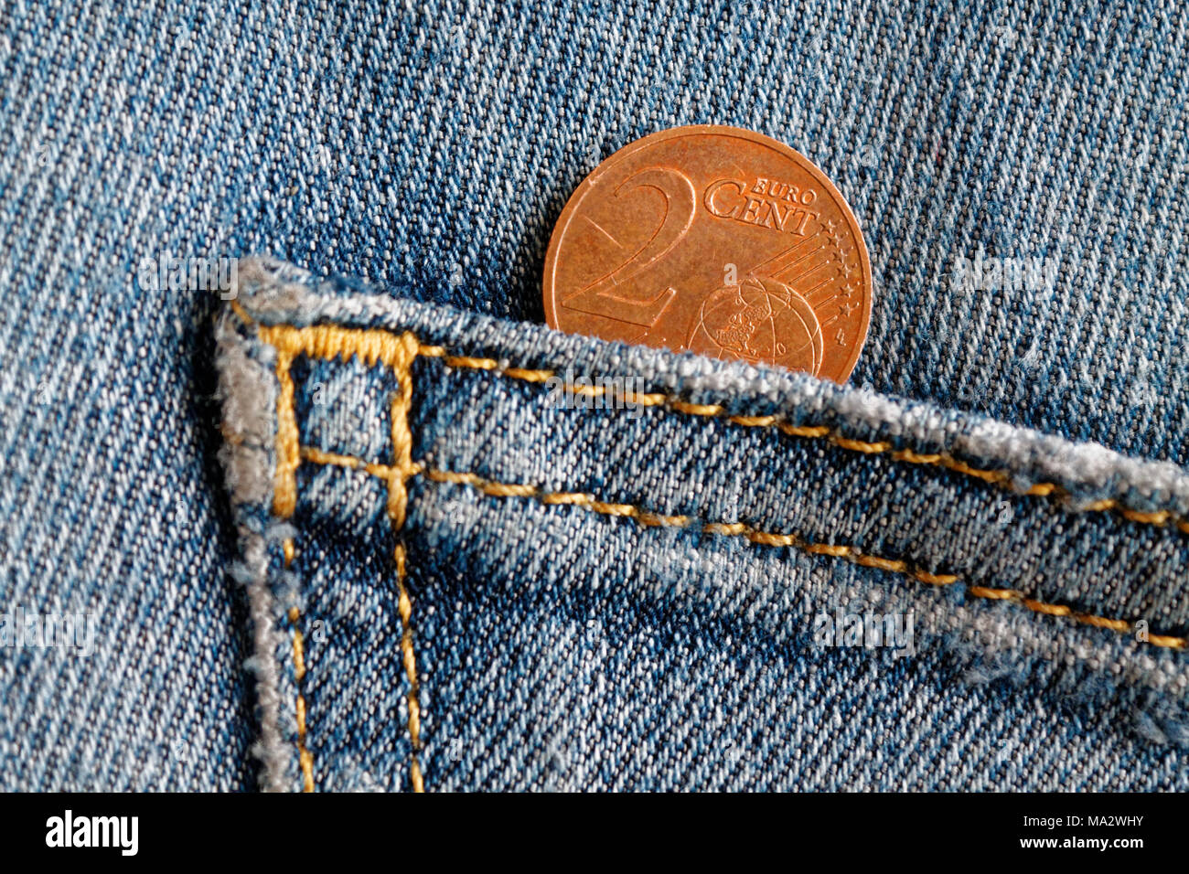 Euro coin with a denomination of 2 euro cent in the pocket of old blue denim jeans Stock Photo