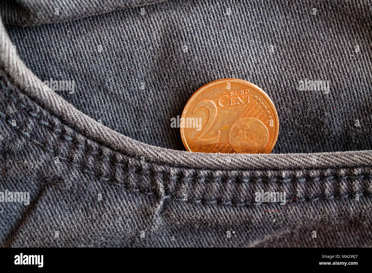 Euro coin with a denomination of 2 euro cent in the pocket of worn blue denim jeans Stock Photo
