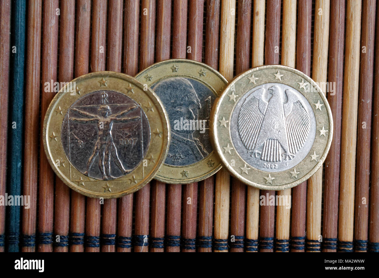 Three euro coins lie on wooden bamboo table in a row Denomination is ...