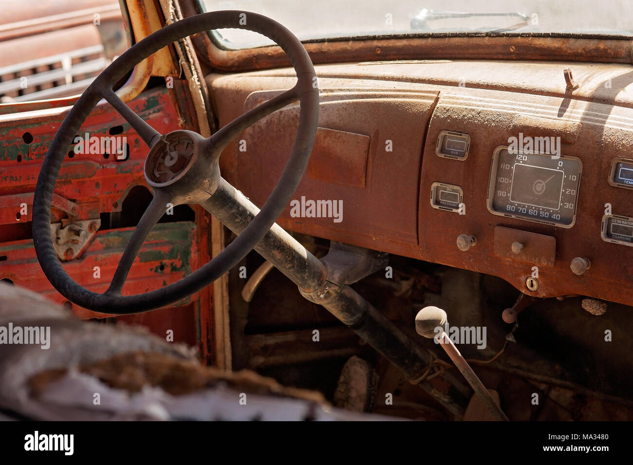 The interior of an old, rusty, antique vehicle showing the steering