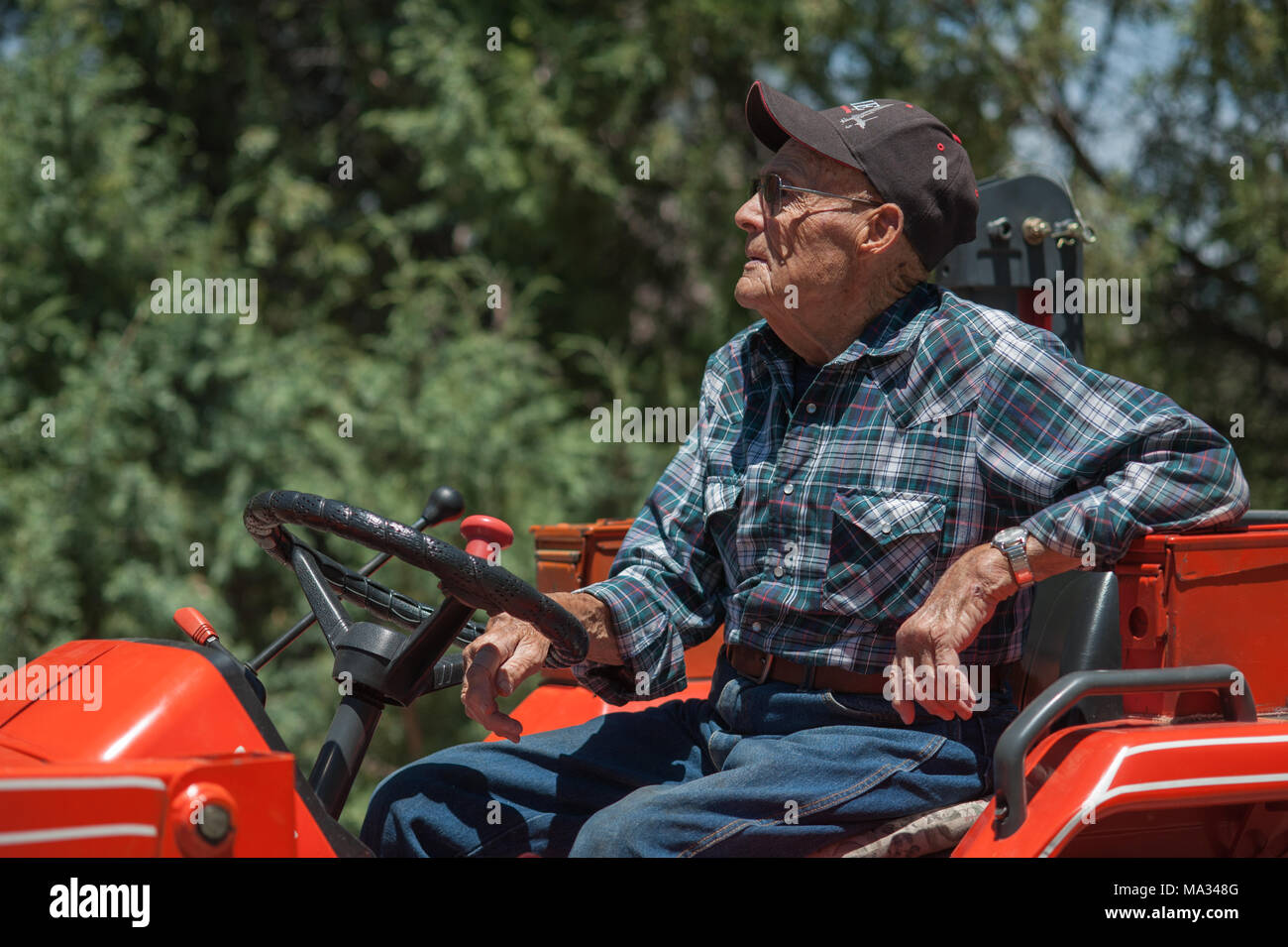 A candid portrait of a senior male farmer sitting on a tractor. Stock Photo
