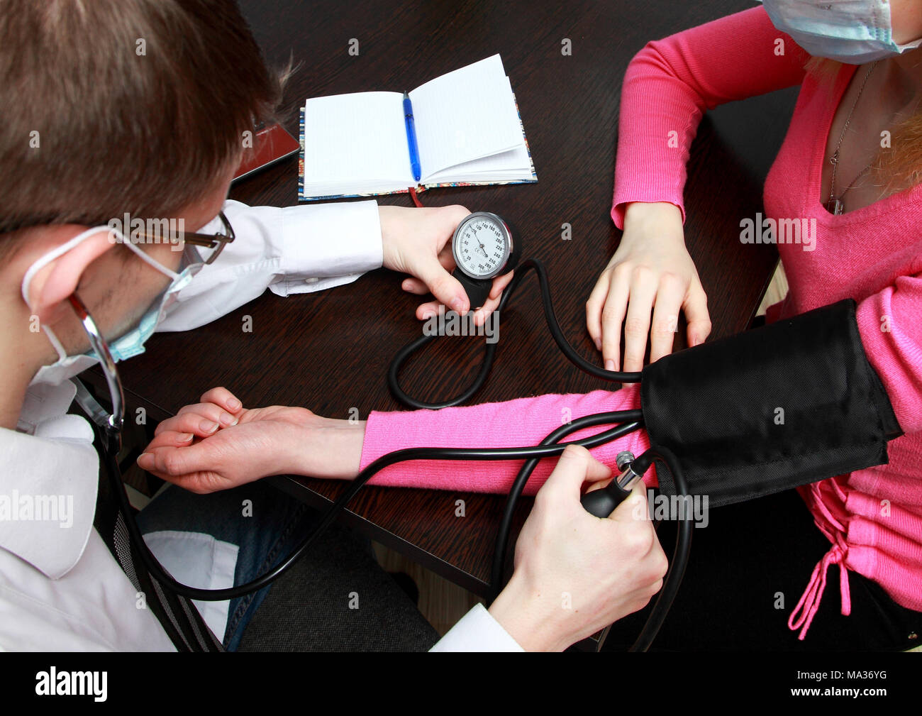 The doctor examines the readings on the sphygmomanometer when measuring the blood pressure. Stock Photo