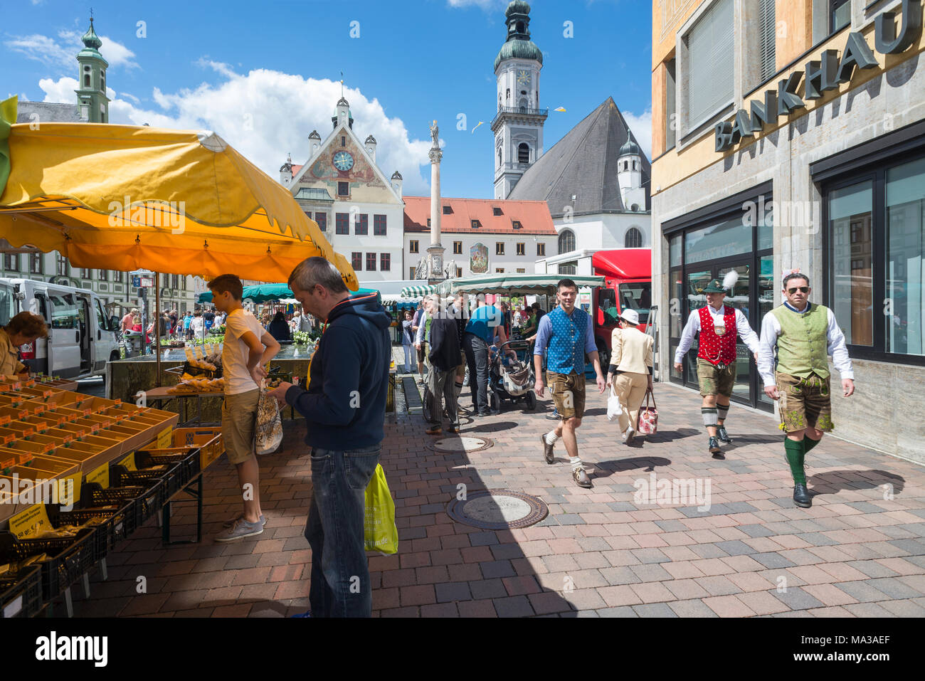 Men in Bavarian dress walk on the busy market in front of the town hall and the church in the old town of Freising, Bavaria, Germany Stock Photo