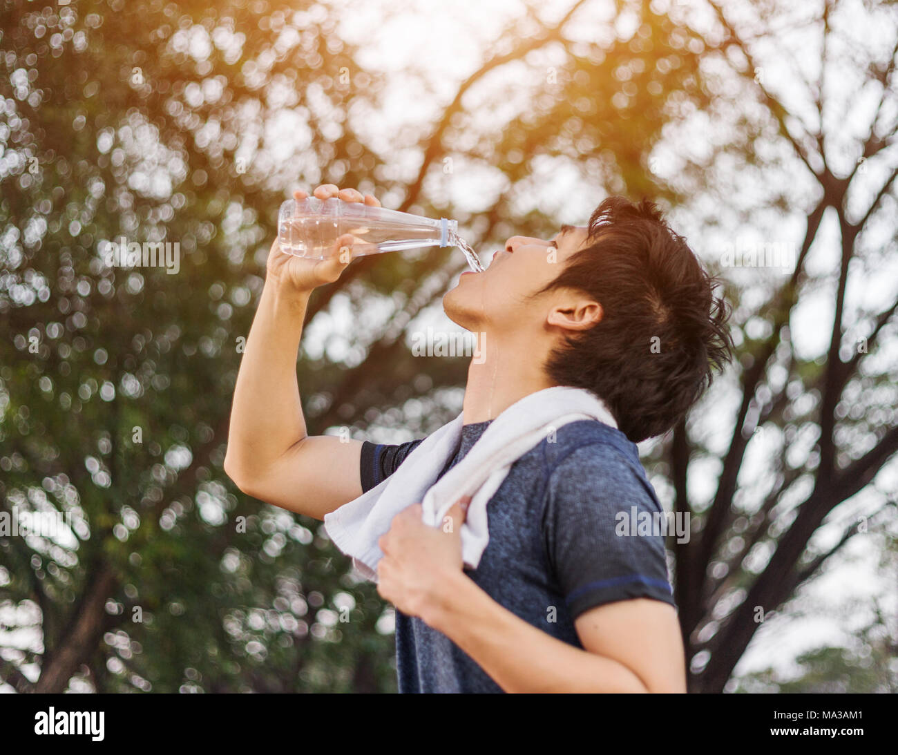 young sporty man drinking water in the park Stock Photo - Alamy