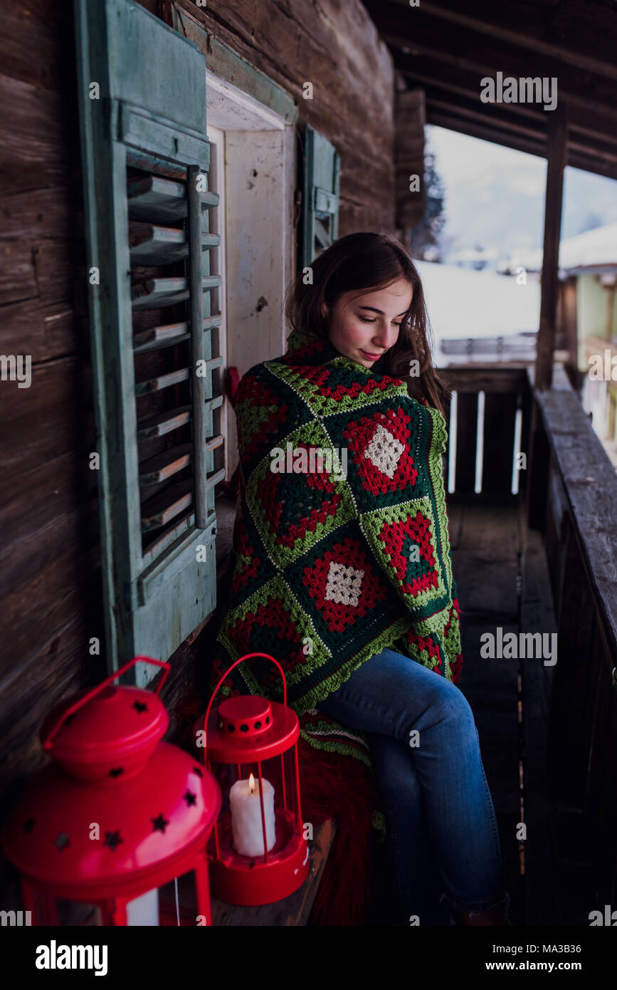 young woman,wrapped in a blanket sitting on the balcony Stock Photo