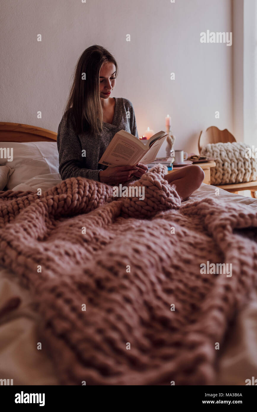 young woman sitting in bed and reading a book Stock Photo - Alamy