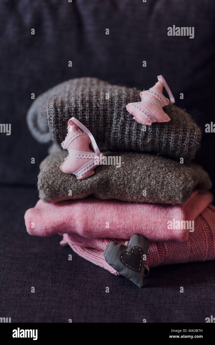 stacked knitted pullovers with fabric tags on sofa, Stock Photo