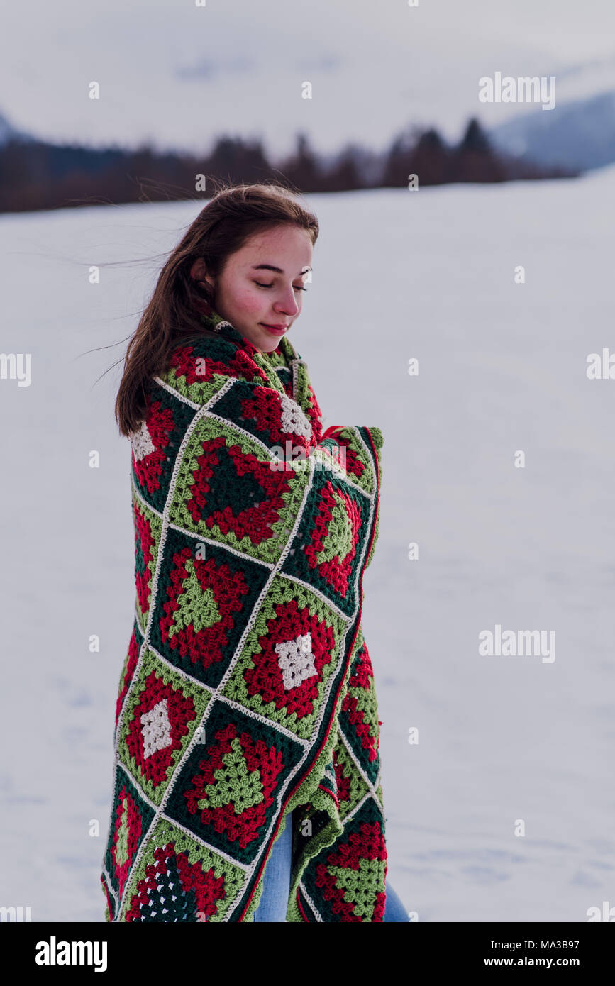 young woman wrapped in a blanket is standing in the snow, Stock Photo