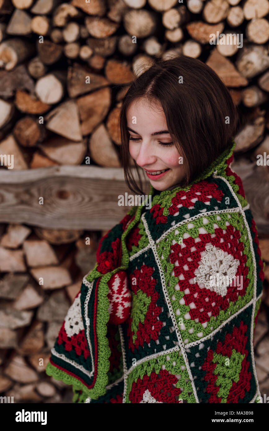 young woman wrapped in a blanket in front of a woodpile,portrait Stock