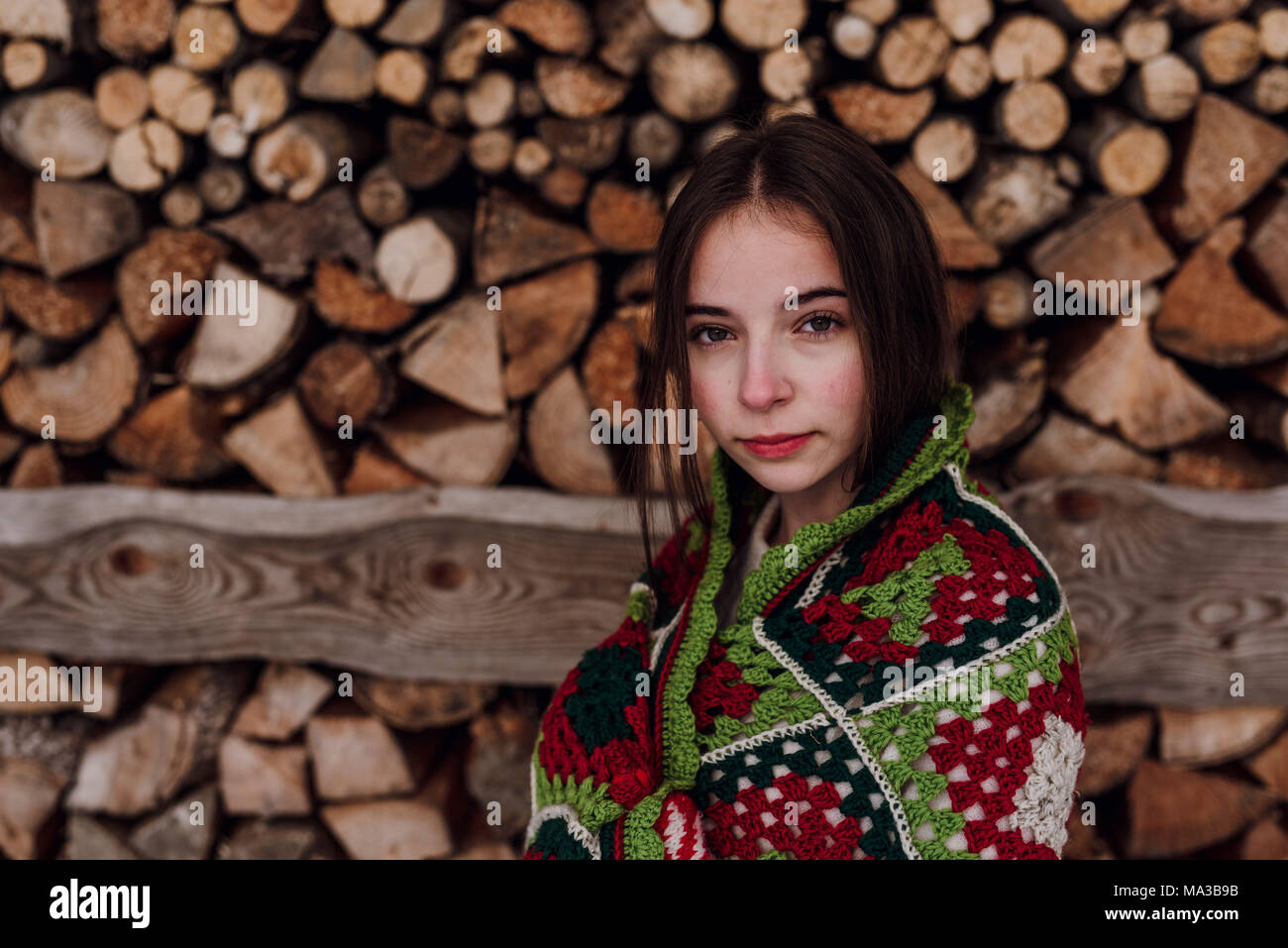 young woman wrapped in a blanket in front of a woodpile,portrait Stock Photo