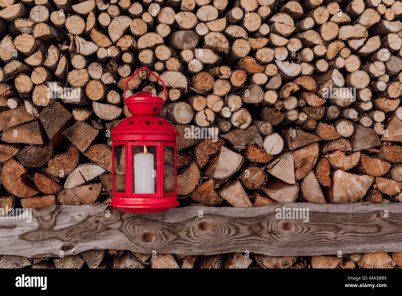 Red lantern in front of piled firewood Stock Photo