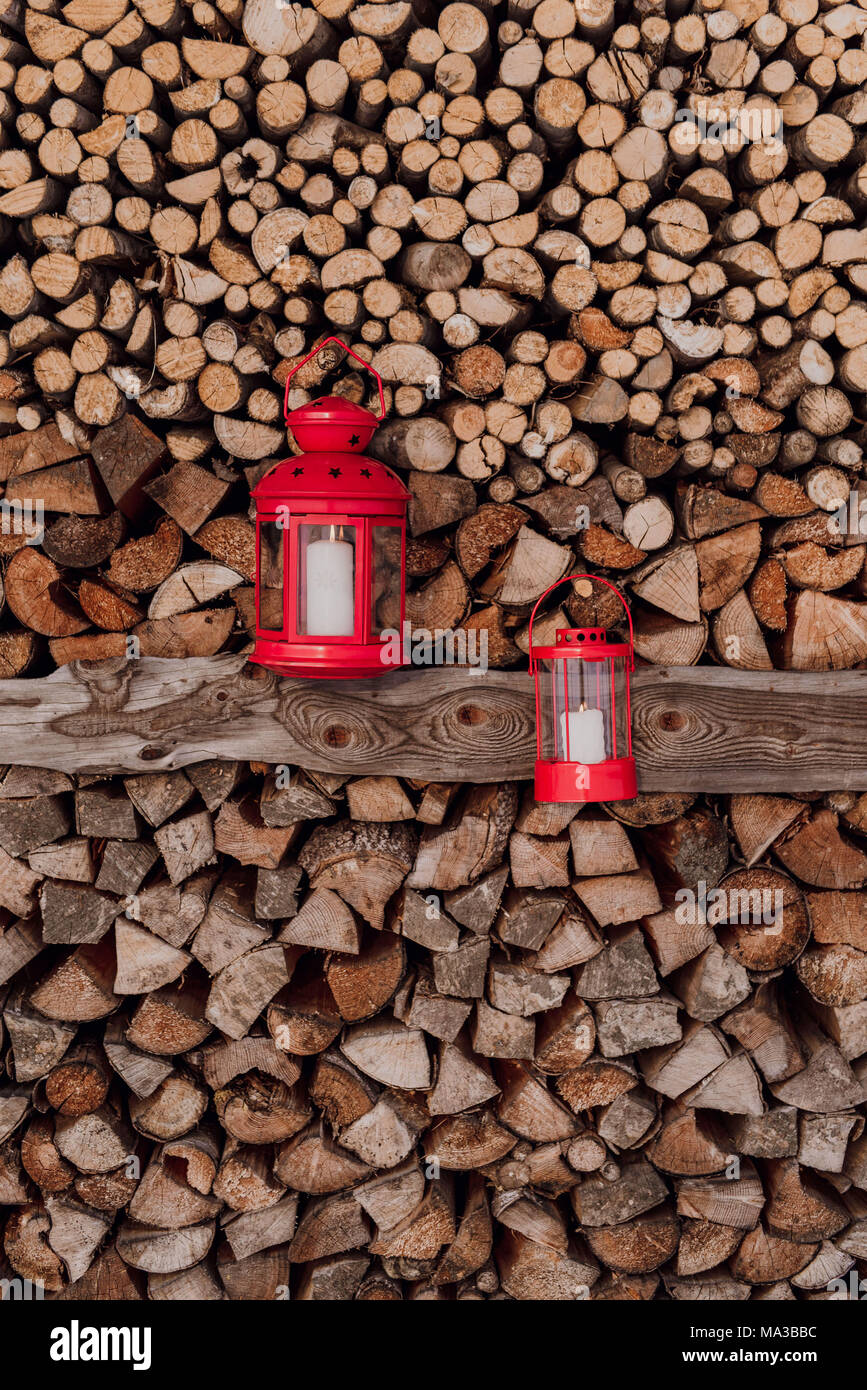 Two red lanterns in front of piled firewood Stock Photo