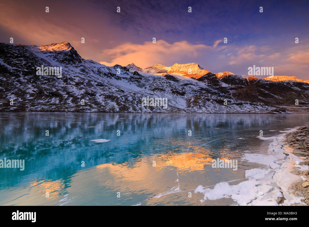 Stunning sunrise on the frozen Lago Bianco(White Lake), Bernina Pass, Engadine, Graubünden, Switzerland. Stock Photo